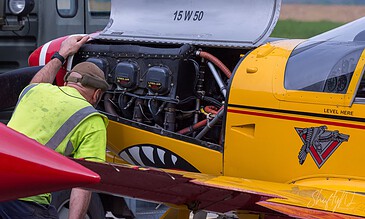 A look under the cowling. Mechanic checking the Lycoming engine of a yellow SF.260 under the open cowling at Beauvechain Air Base, Belgium, April 2018.