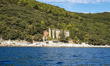 2. Charming dam amidst green hills and tranquil lake, capturing the peaceful beauty of nature and engineering in harmony. 1. A scenic view of a dam structure nestled among lush green hills beside a calm blue lake under a bright sky.