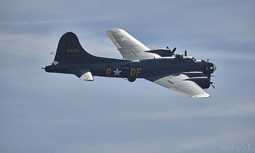 A historic WWII-era aircraft in flight with a sleek design and distinctive markings captured during a high-altitude event. Aviation photography capturing a vintage military aircraft flying in a clear blue sky, showcasing detailed features and historical design elements.
