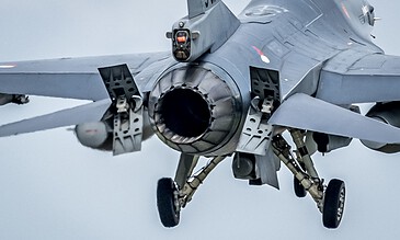 High-speed fighter jet landing, advanced military aircraft in flight, sleek aerodynamic design, gray sky background.