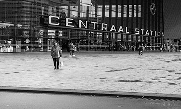 1. People walking outside Rotterdam Central Station in black and white, capturing urban life and architecture.