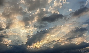 Capture of a stunning sky with vibrant clouds and sunlight breaking through in a breathtaking sunset scene. Vivid sunset sky with dramatic cloud formations showcasing warm golden hues and contrasting dark shadows.