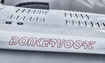 1. Close-up of a white sports car hood with water droplets, featuring red "Donkervoort" text and ventilation slats under cloudy sky.