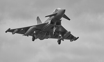 High-speed fighter jet soaring through the sky, showcasing sleek design and advanced aviation technology in a black-and-white photograph.