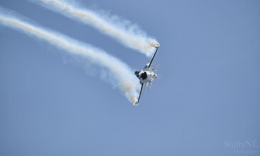 2. Capturing thrilling moments of a fighter jet in mid-air during an air show with dramatic smoke trails. 1. A fighter jet performing an aerial stunt with smoke trails against a clear blue sky.