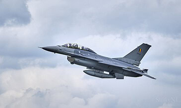 A Belgian F-16 fighter jet flying through cloudy skies during an airshow event.