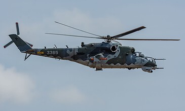 Aerial view of a military helicopter flying in the sky with clouds, showcasing aviation photography.