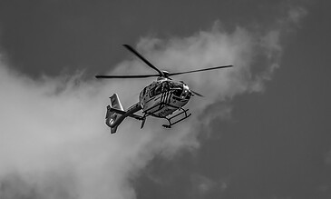 Aerial helicopter in flight against cloudy sky, showcasing dynamic movement and modern design.