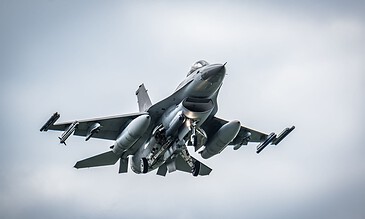 1. F-16 fighter jet soaring through the sky with afterburners on, capturing an aerial combat moment.