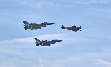 2. A dynamic aerial display featuring two modern fighter jets and a vintage aircraft flying in formation against a bright blue sky. 1. Three fighter jets soaring through a blue sky during an airshow, showcasing aerial agility and military aircraft capabilities.