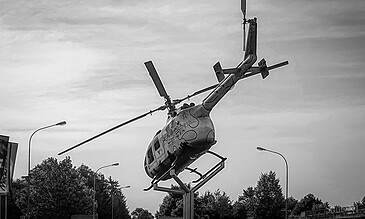 Helicopter monument displayed outdoors, featuring a striking sculpture for photography, perfect for capturing memorable moments in one place. A black and white photo of a helicopter mounted on a stand against a cloudy sky, capturing an artistic and dynamic moment.