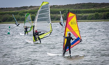 1. Wind surfers gliding across the water on a windy day, showcasing thrilling outdoor water sports and adventure activities.