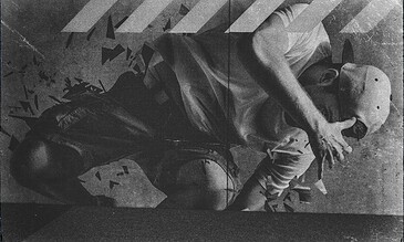A man crouched on the ground with fragmented geometric shapes around him, captured in black and white, creating a dynamic and artistic scene of abstract moments.