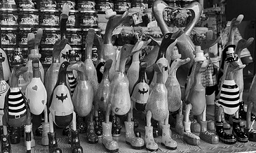 Collection of decorative wooden animal figurines including rabbits, ducks, and birds displayed on a store shelf in black and white.