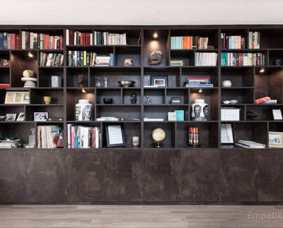 Full view of dark coloured floor to ceiling display unit with asymmetrical shelves and bottom storage closets