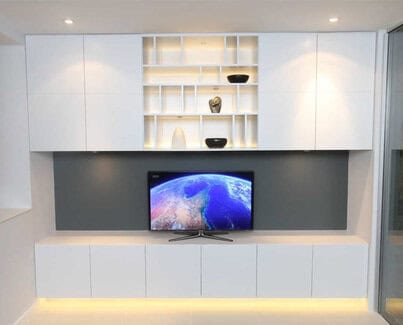 Bespoke White painted low TV media unit with 4 closets above and LED light display shelves