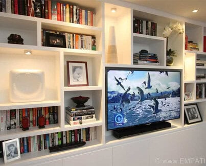 Large ceiling high TV media unit with asymmetrical surrounding shelves and bottom closets