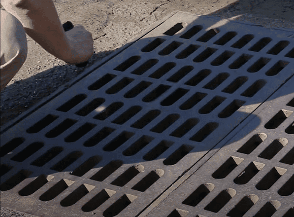 A field worker examines a storm drain