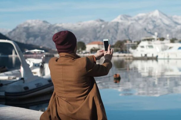 Montenegro - woman in winter clothes taking photo at harbor