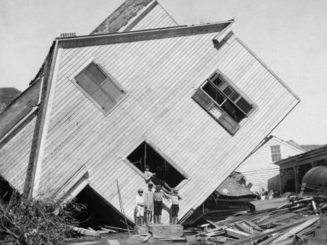 A house turned sideways after the Galvestone Hurricane, with kids standing in front of it