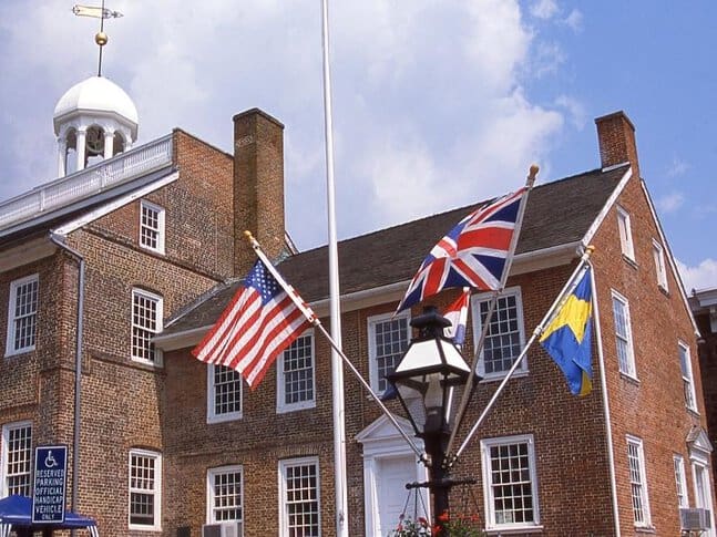 An old courthouse building with flags flying in front of it in New Castle, the original capital of Delaware