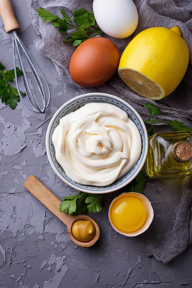 Homemade mayonnaise in a dish with ingredients used nearby.