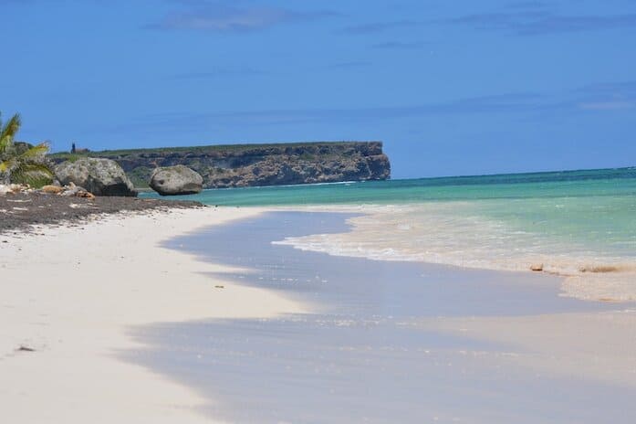 The shoreline on a Puerto Rican beach, where you can pitch a tent for Caribbean camping! The landscape is calm sea with gentle waves and clear blue skies.