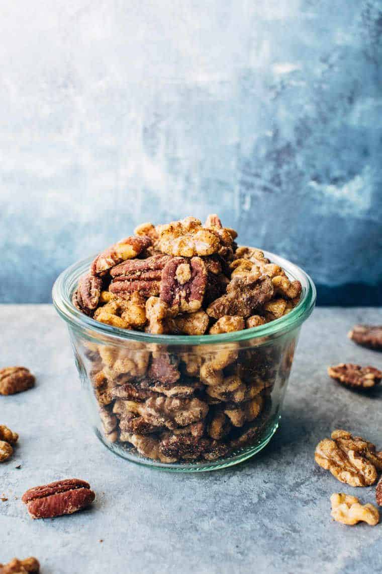 glass bowl of different roasted nuts on a stone surface