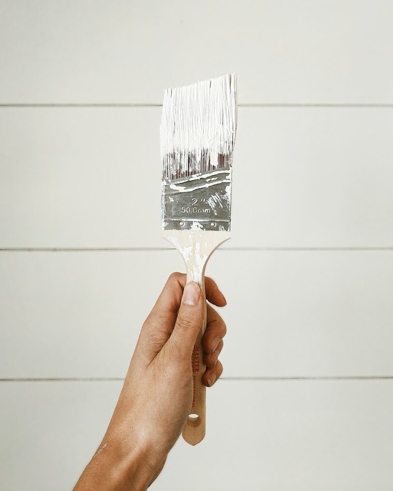 a hand holding a paint brush with white paint on it