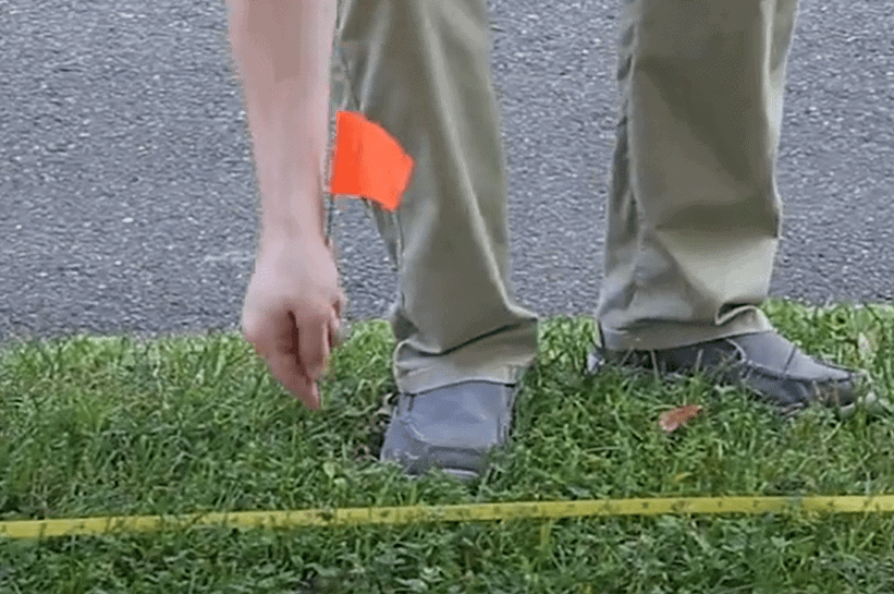 A worker plants a flag in the field marking a buried utility