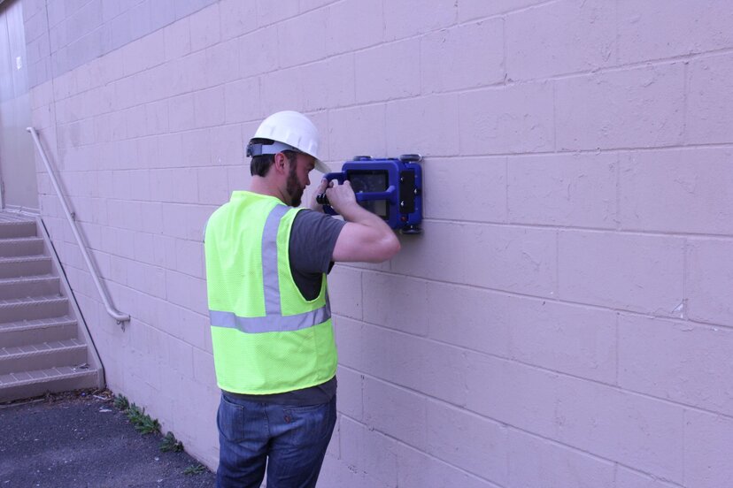a person uses a handheld concrete scanning GPR against a wall
