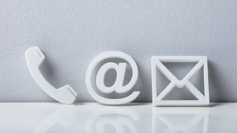 a close-up of phone, social media, and email icons leaning against a white wall
