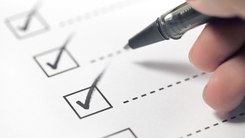 a hand with a black pen marking on a checklist box