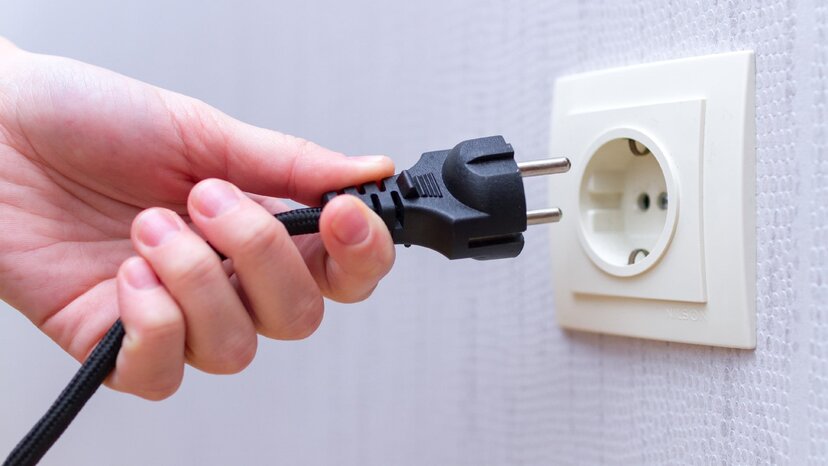 a person’s hand is plugging a cord into an electrical outlet