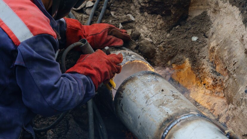 a plumber fixes pipes outdoors