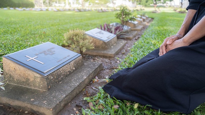 Person kneeling at grave | What Is Grave Mapping and Why Would Someone Do It? | US Radar