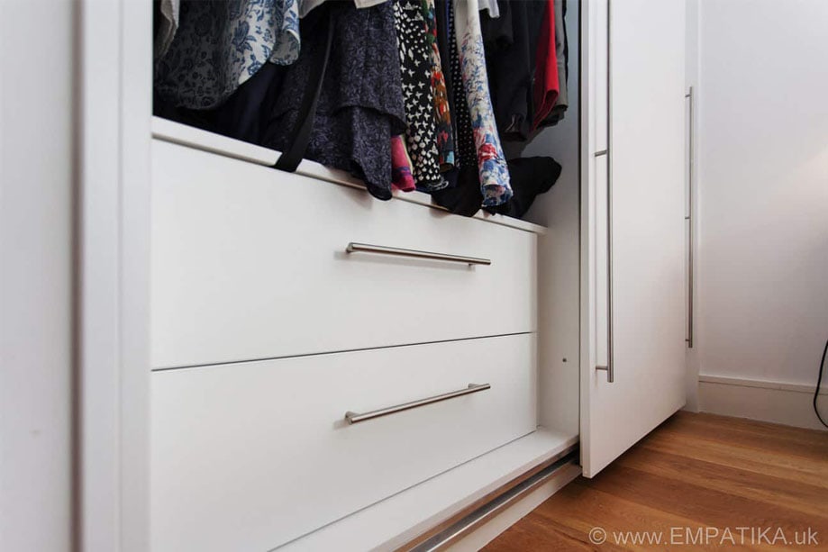 Bespoke sliding wardrobe with two drawers inside that is clearly visible amongst hung clothes