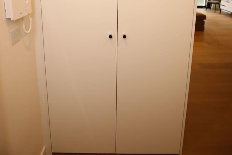 Full view of sleek hallway cupboard with 2 floor to ceiling doors painted White with small steel handles