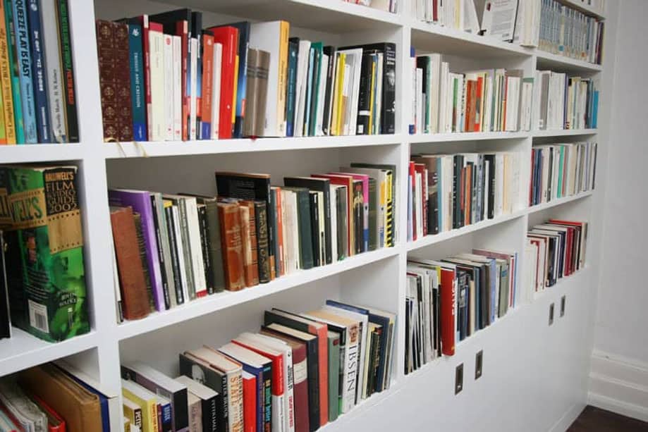 Side view of wall to wall library bookcase shallow shelves all painted White