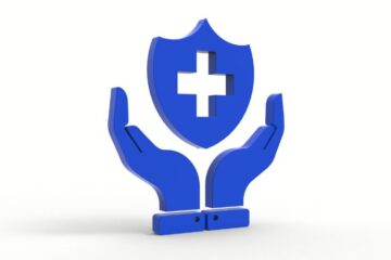 Blaues Schutzsymbol mit Kreuz und Händen auf weißem Hintergrund, symbolisiert den Vergleich von privater und gesetzlicher Krankenversicherung für Ärzte.