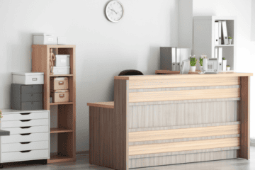 Empfangsbereich einer modern gestalteten Arztpraxis mit Holztheke, Aktenordnern und Dekoration.