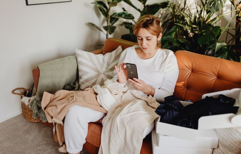 Frau auf Sofa informiert sich per Smartphone über digitale Patientenaufklärung zuhause