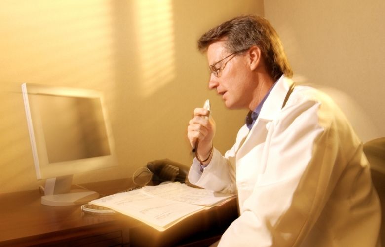 Arzt nutzt Spracherkennung zur digitalen Dokumentation medizinischer Daten am Schreibtisch