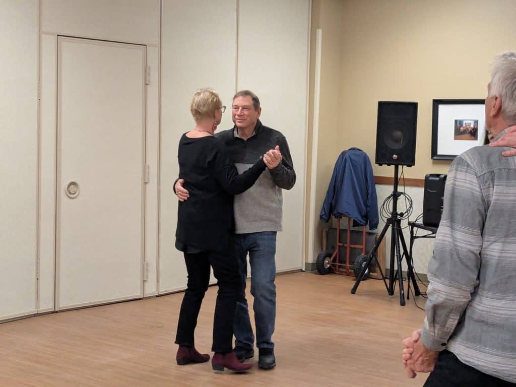Two people dancing at Join Our Team event with a third person watching.