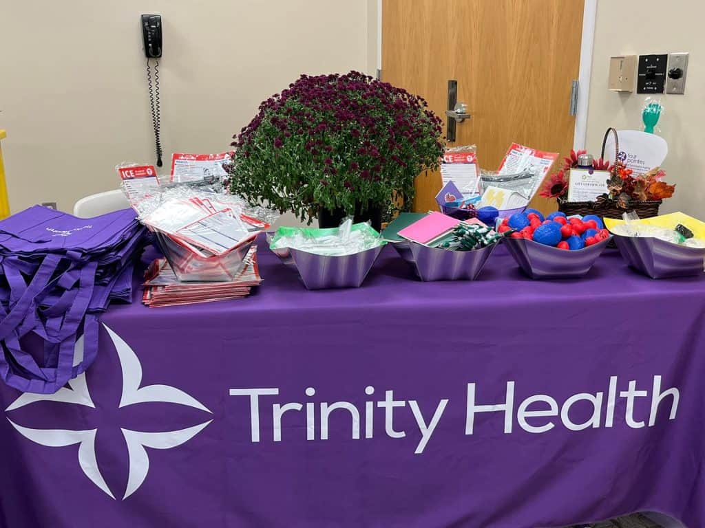 Trinity Health promotional table with flowers and giveaways.