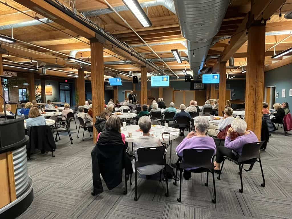 Business networking event with people seated at tables in a modern conference room.