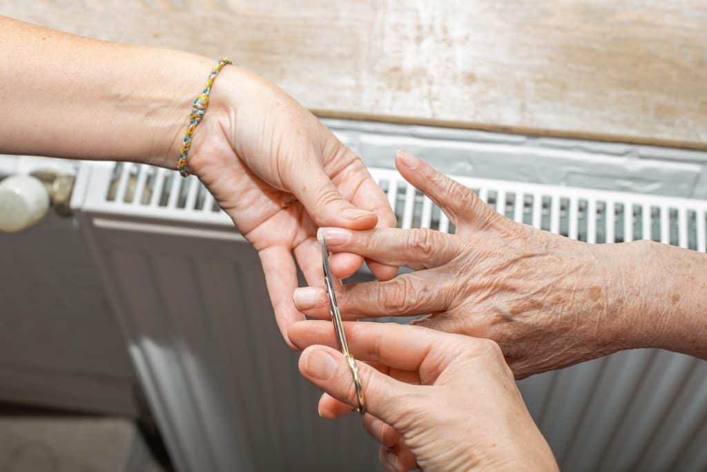 Caregiver providing hand care support to elderly person at home.