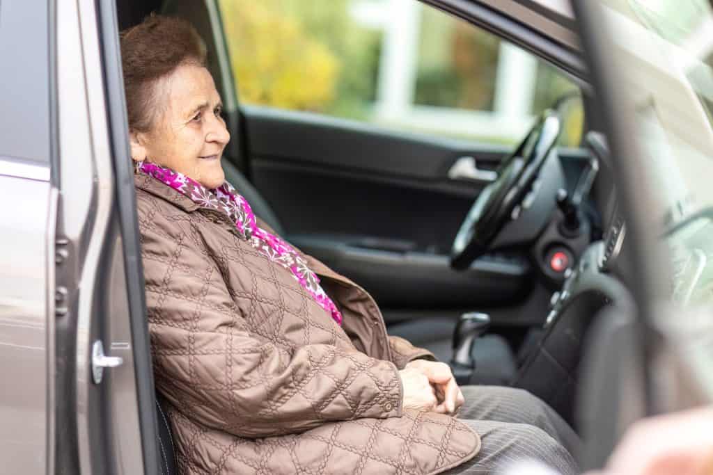 Elderly woman sitting comfortably in car for accessibility and mobility.