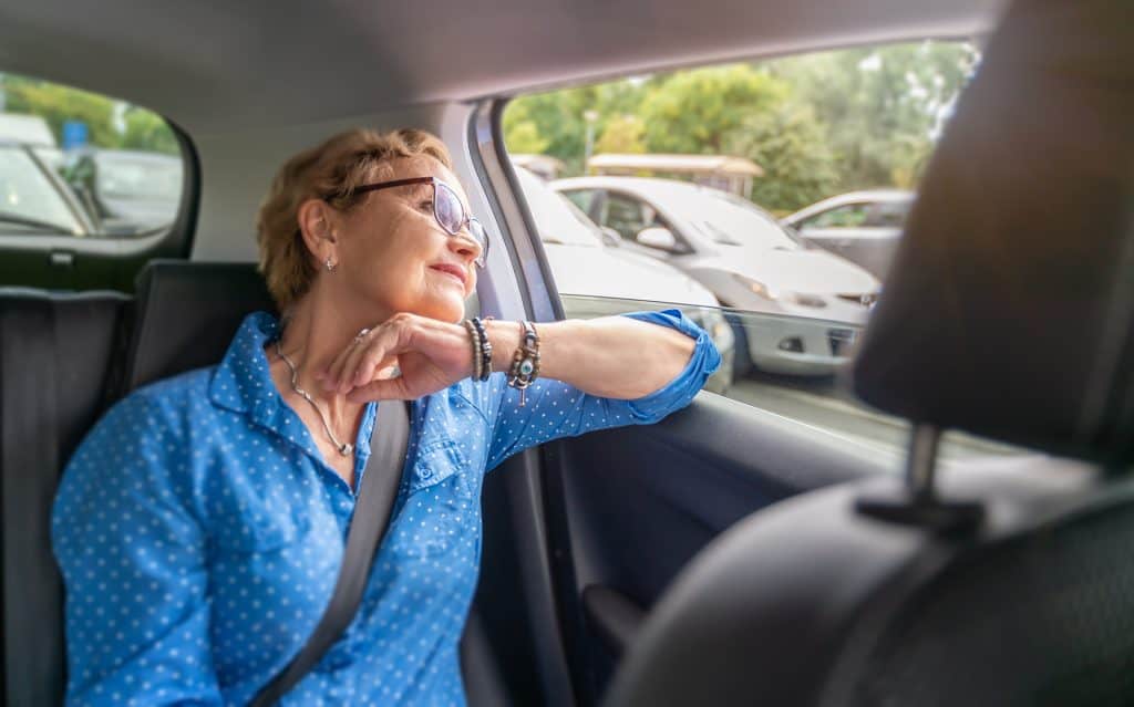 Elderly woman looking out car window, enjoying the view.