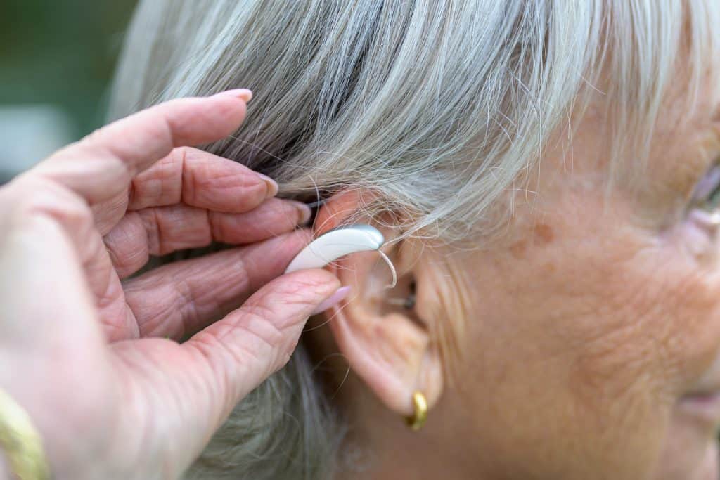 Senior woman getting a hearing aid fitted by a healthcare professional.